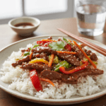 Budget-friendly Beijing beef served over steamed rice with vegetables and sesame seed garnish.