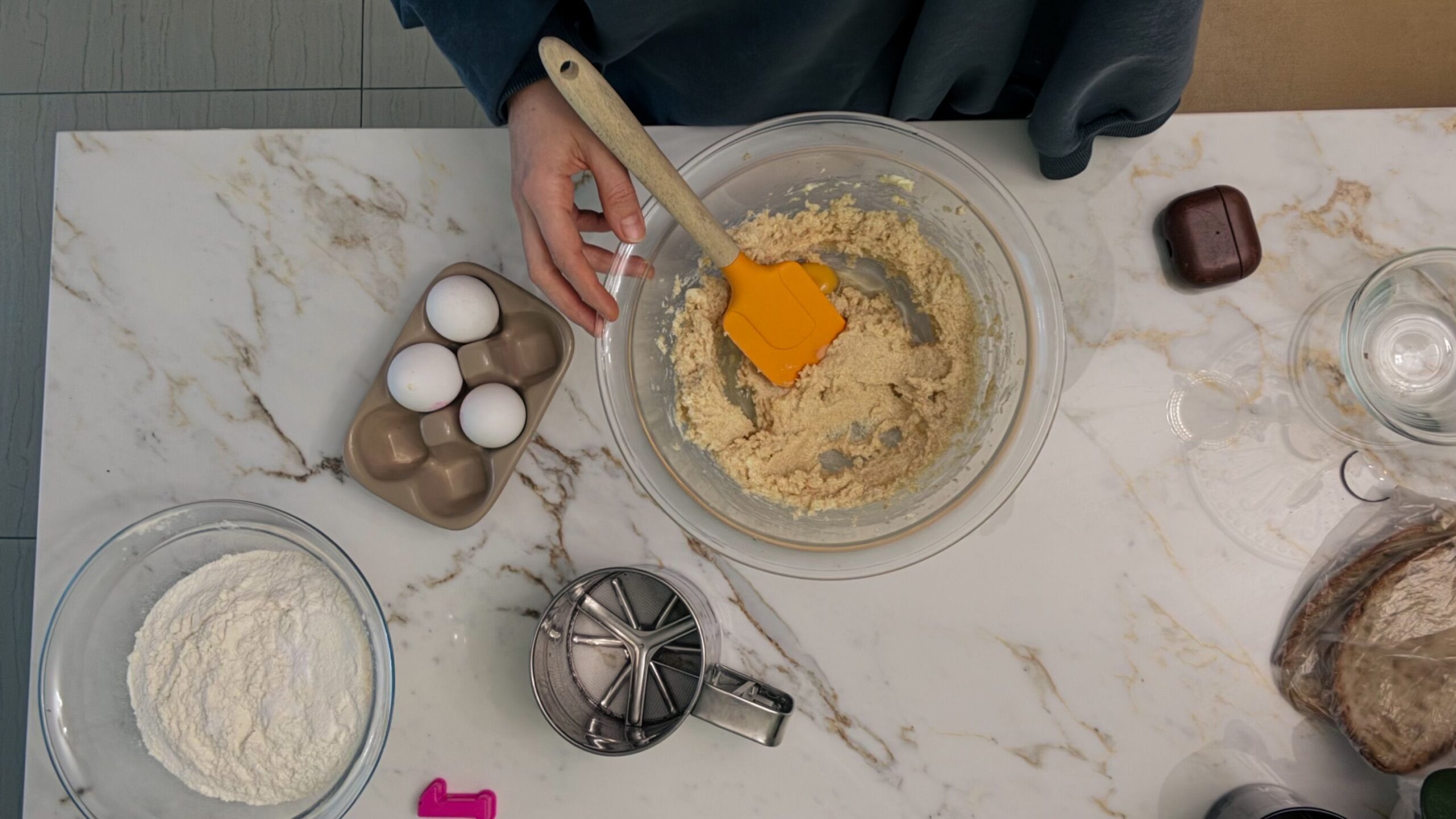Overhead flat lay of measured baking ingredients and a recipe notebook on a kitchen work surface