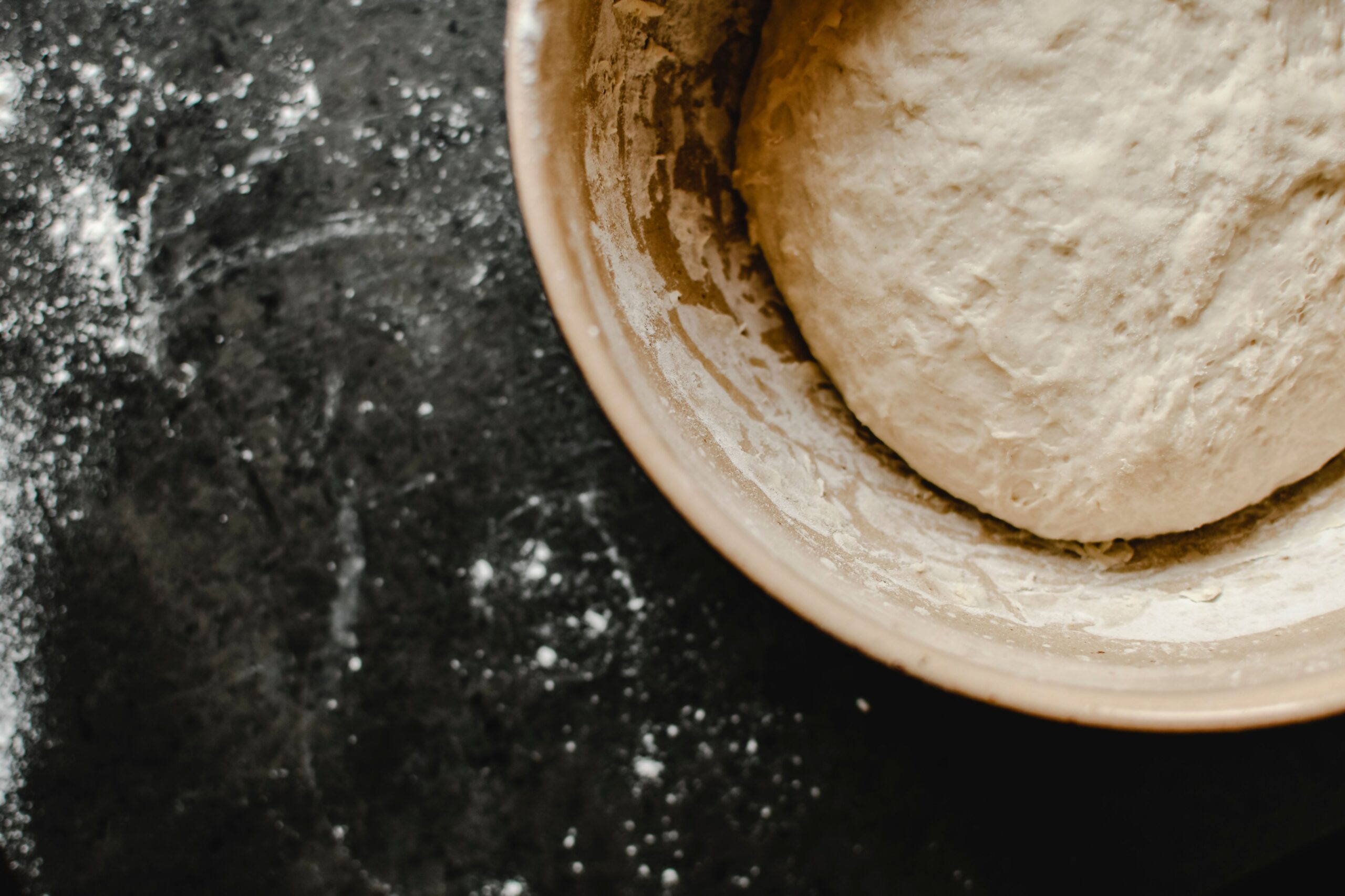 Slack, shiny bread dough in a bowl during bulk fermentation, showing the wet and extensible texture of a high-hydration dough