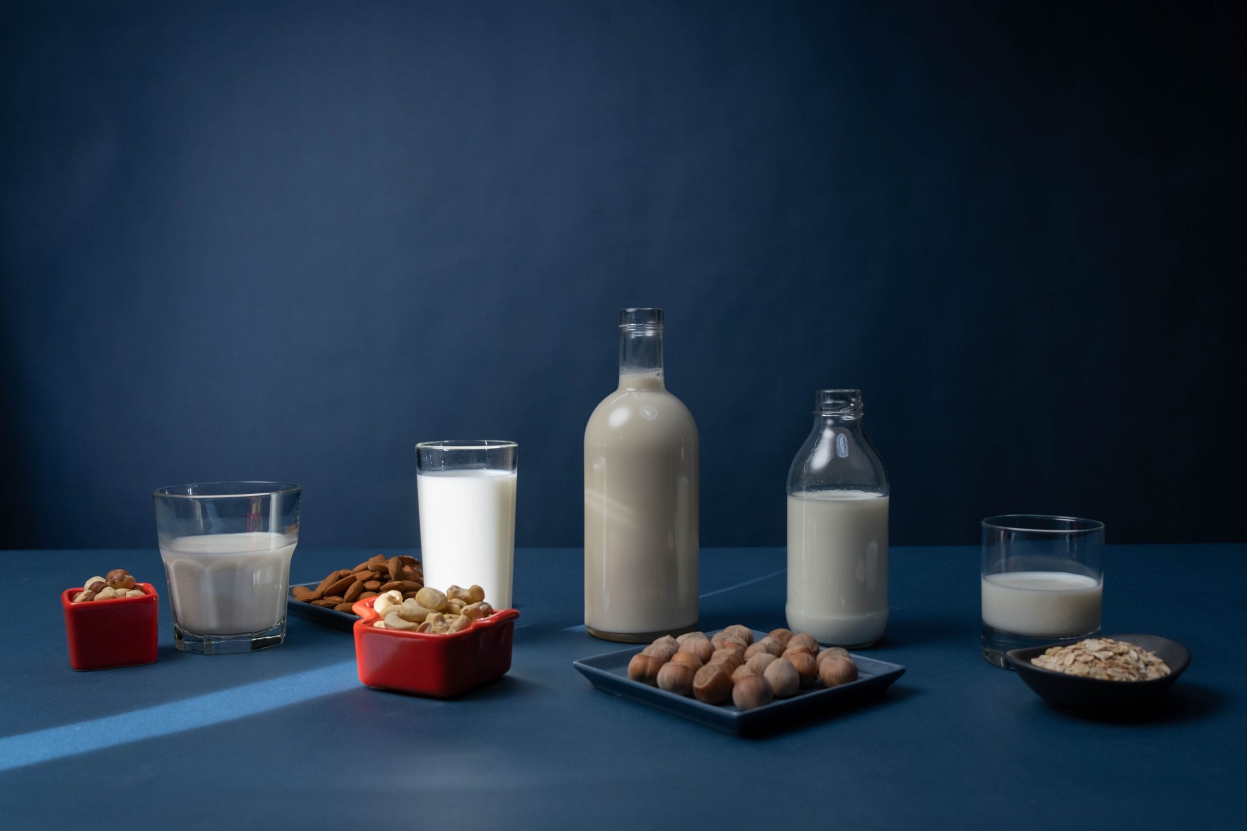 Row of plant-based milk cartons including oat, soy, almond, and coconut milk on a light kitchen surface