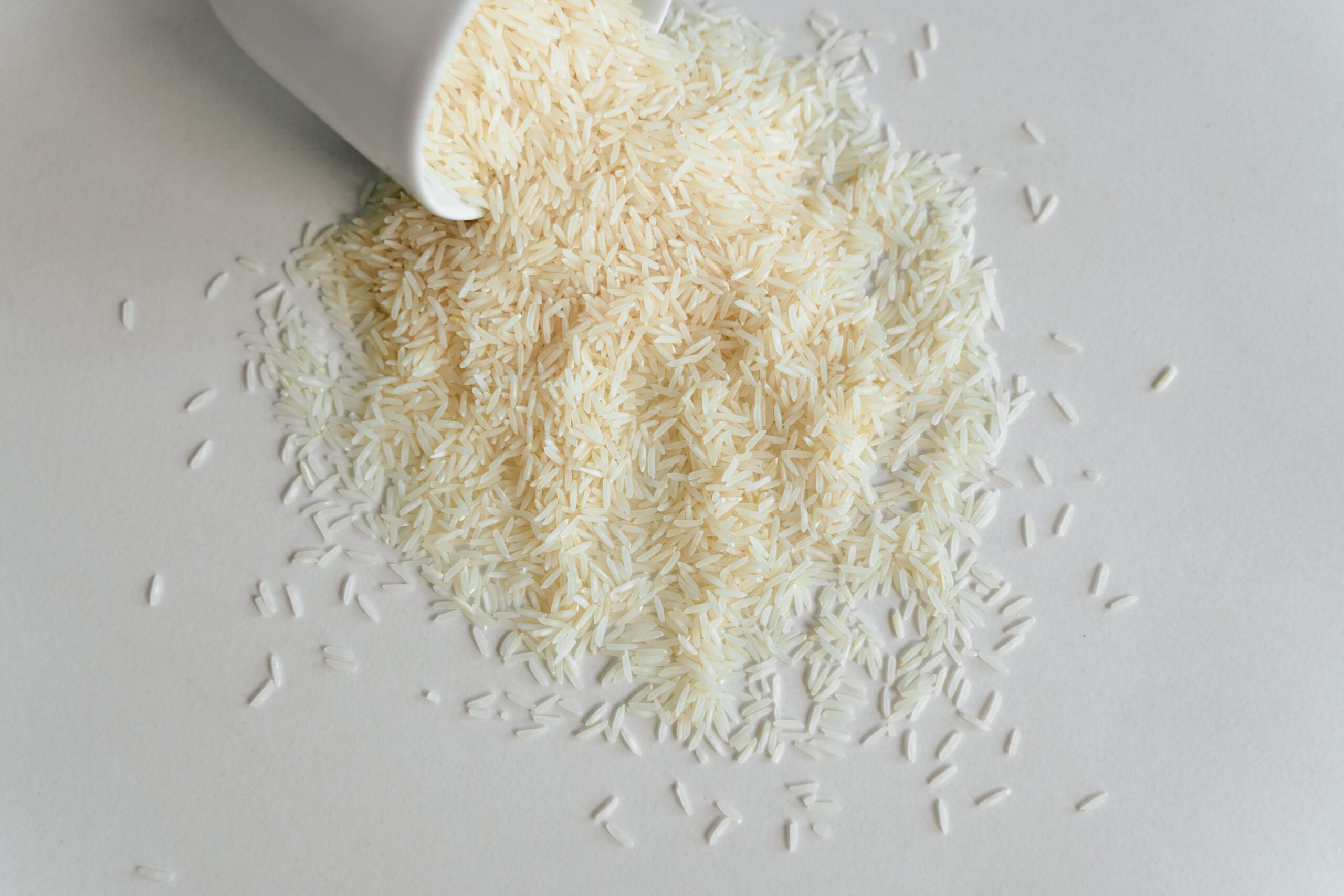 Overhead view of dry white rice in a measuring cup beside water for rice cooking