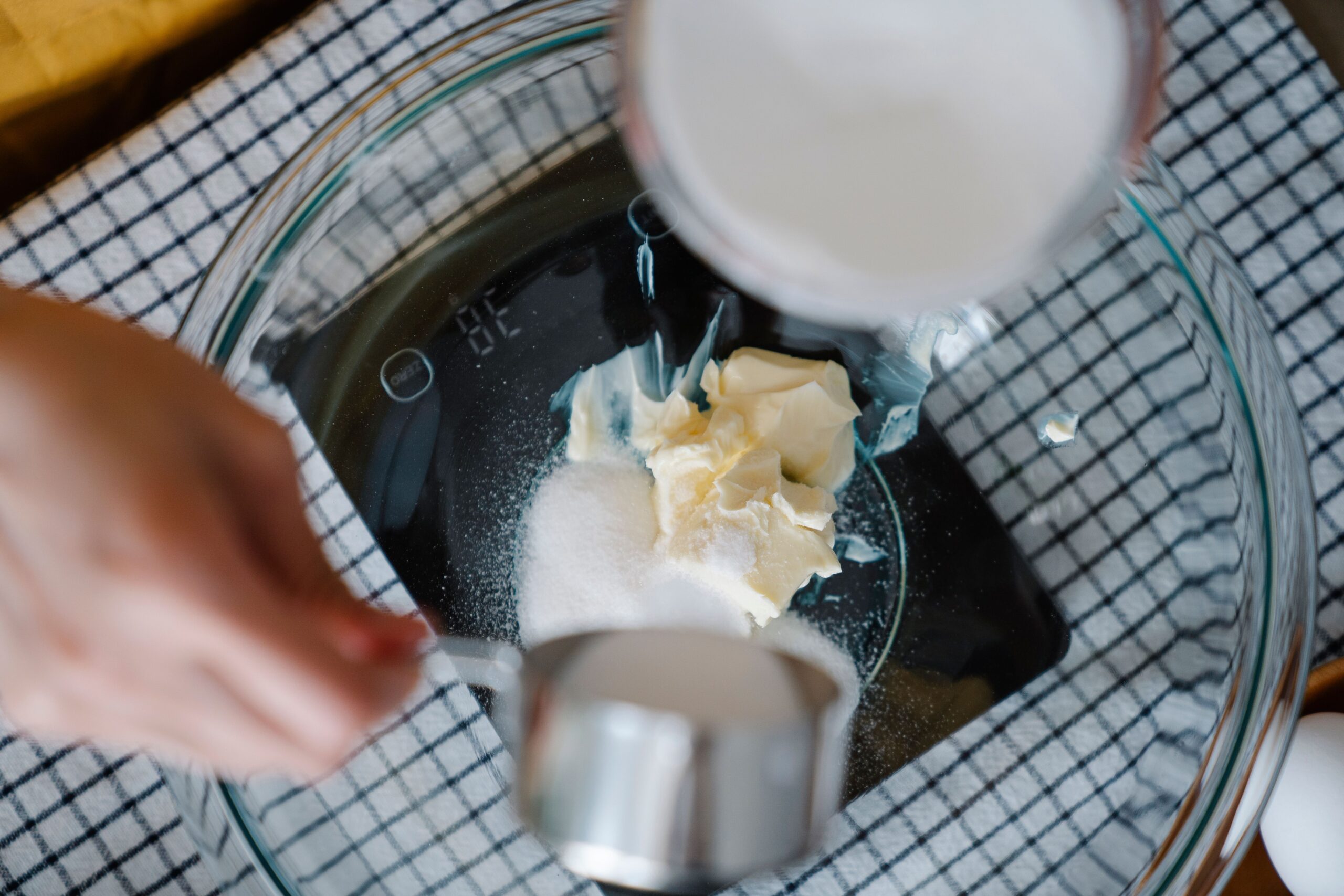 Measuring cup filled with flour beside a kitchen scale showing gram measurements