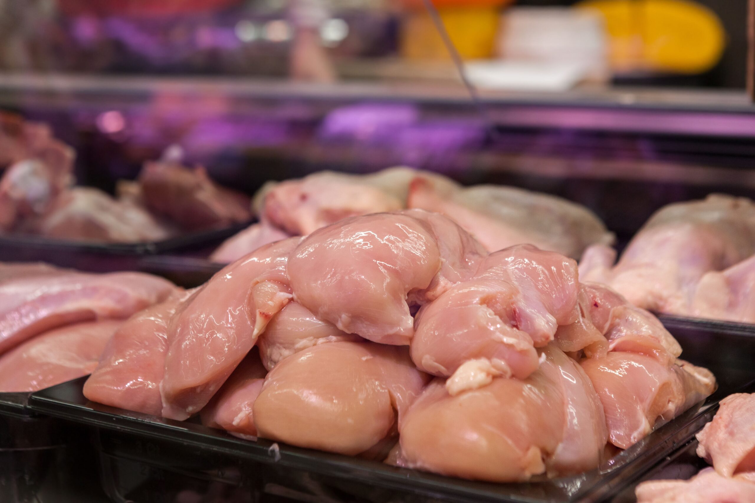 Fresh raw chicken in sealed packaging stored in a refrigerator on a low shelf