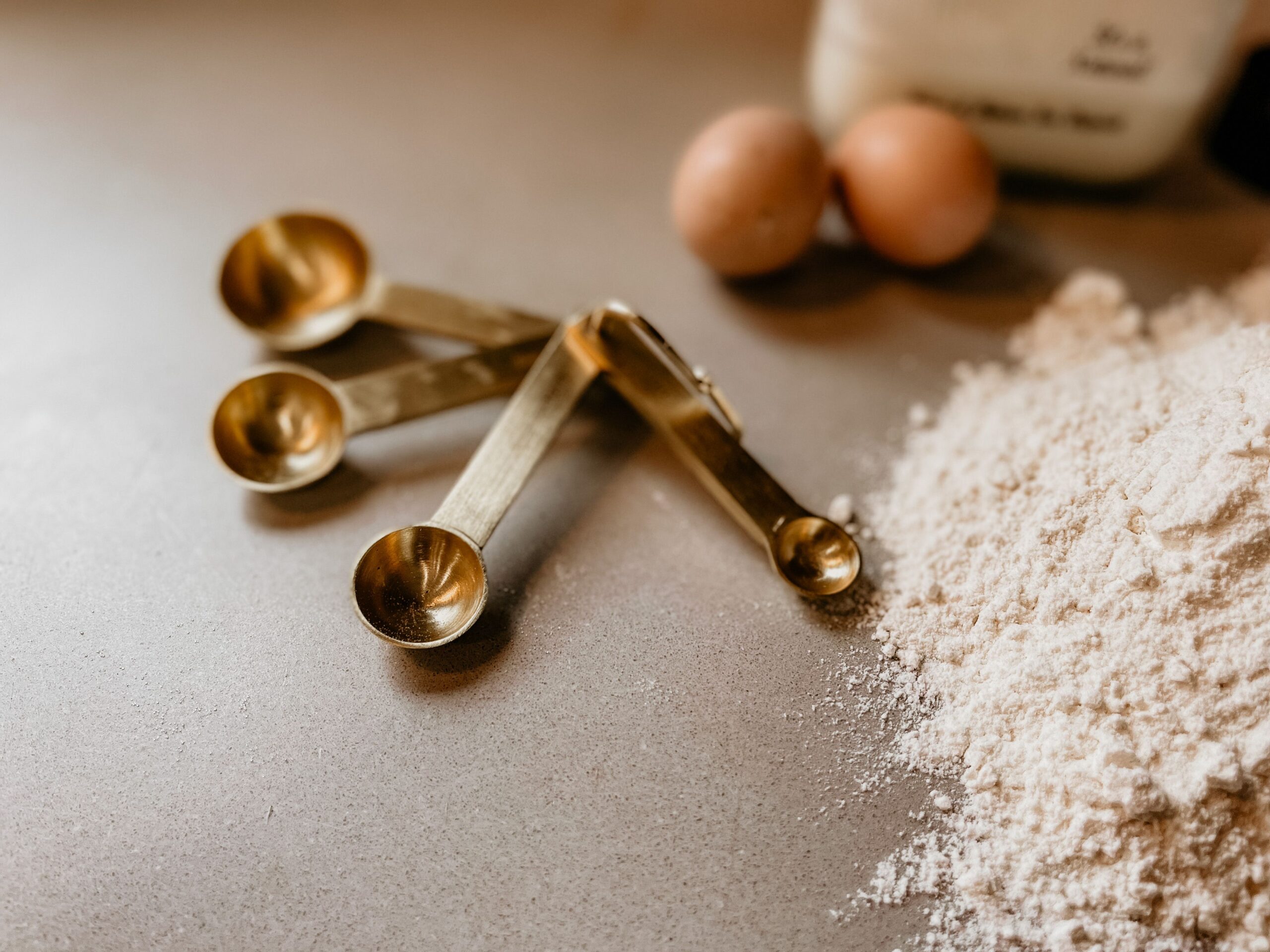 Close-up of measuring spoons filled with baking ingredients laid out on a kitchen counter