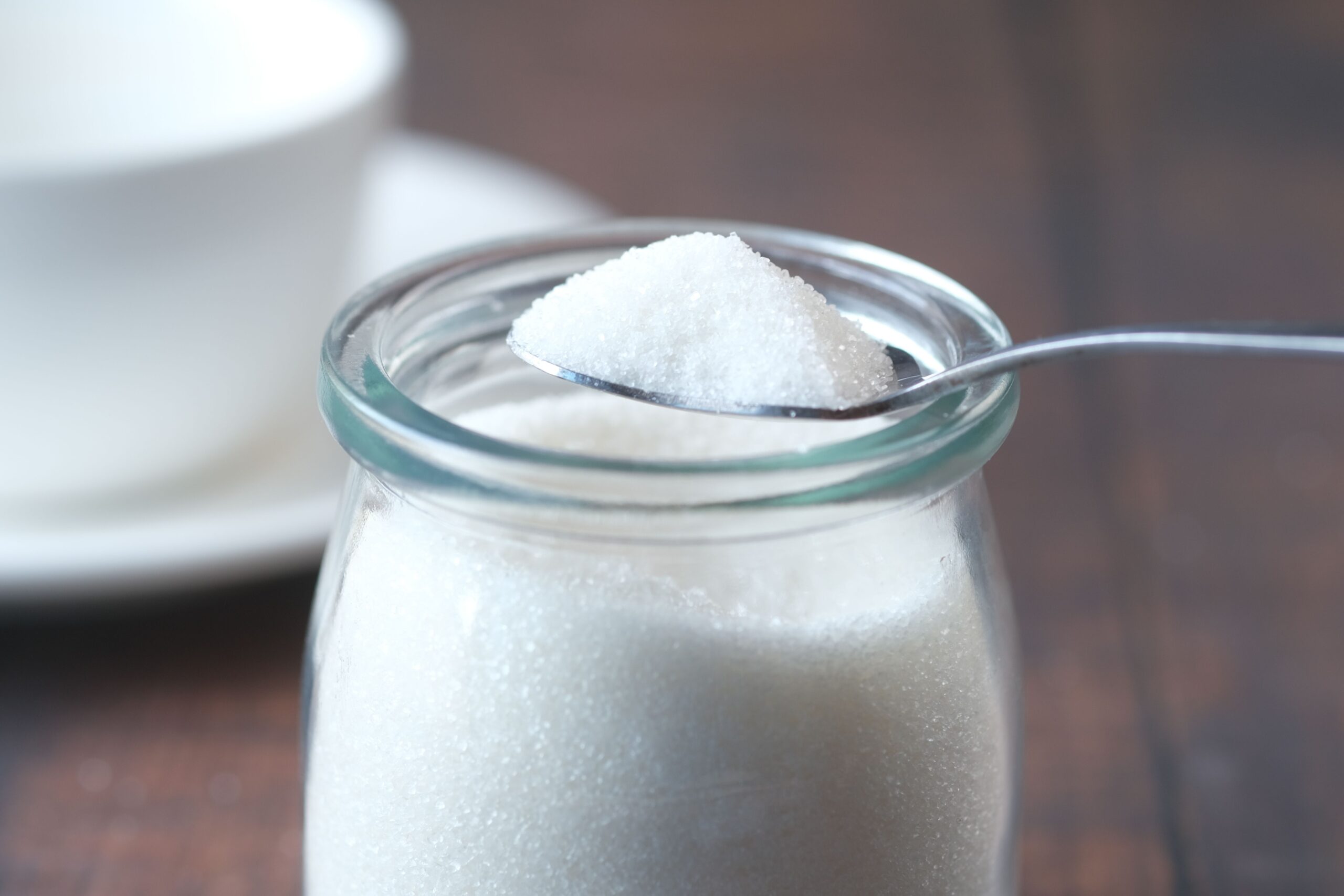 Sugar being carefully spooned into a measuring cup for accurate baking measurements