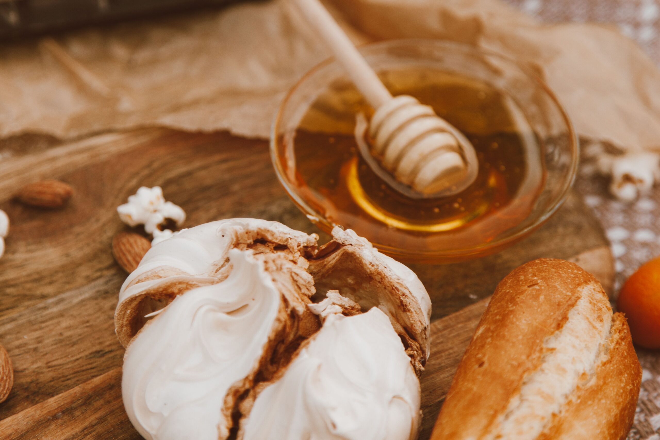 Honey jar alongside a measuring cup of sugar and baking ingredients on a warm wooden surface