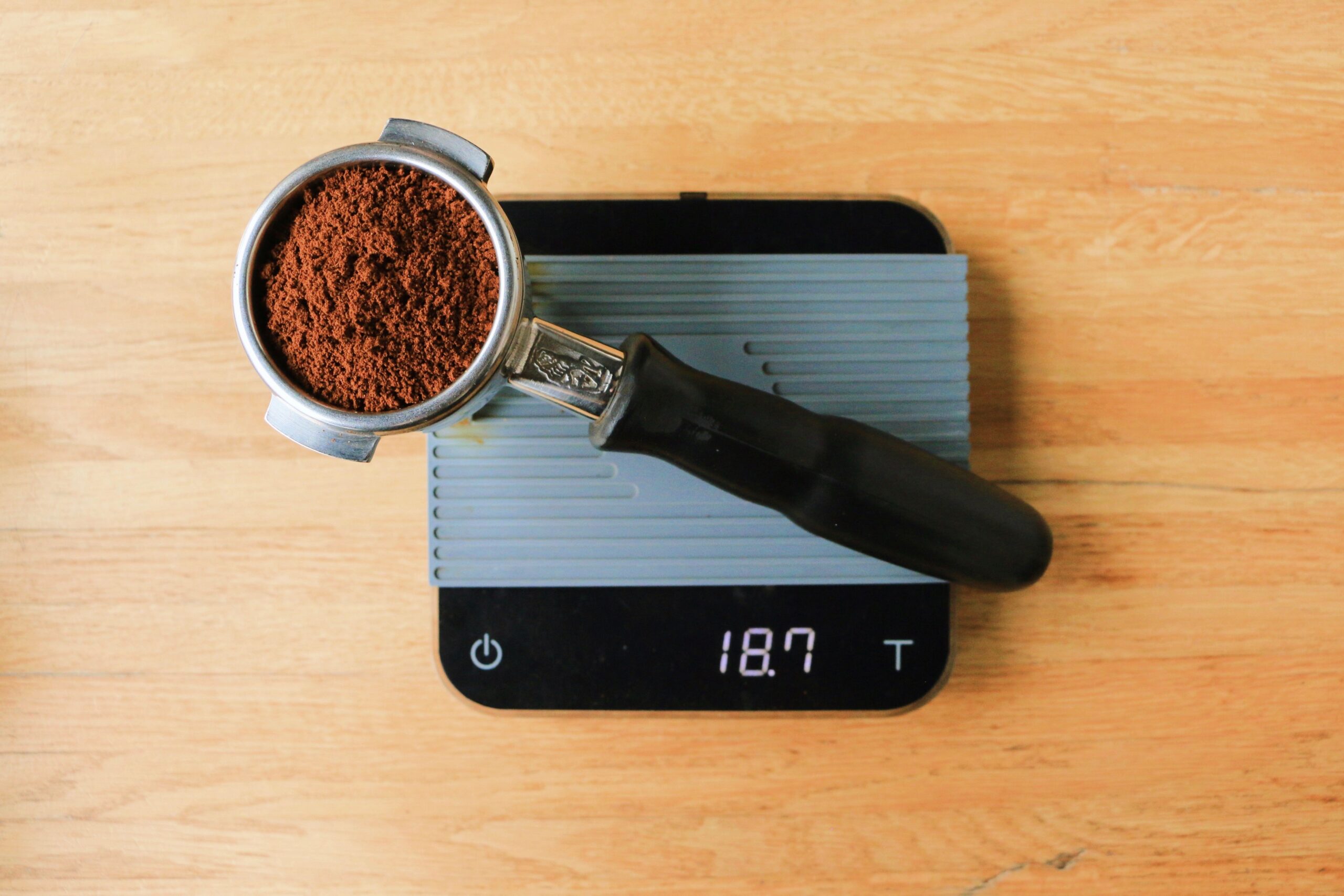 Digital kitchen scale displaying grams while weighing coffee grounds into a pour over filter dripper